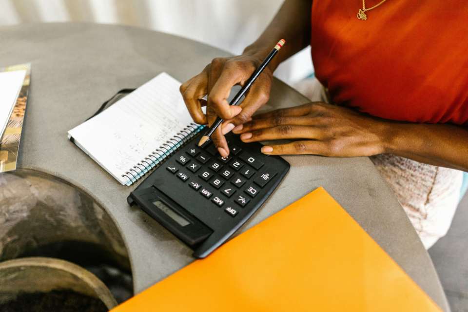 woman calculating budget at table with calculator and notepad